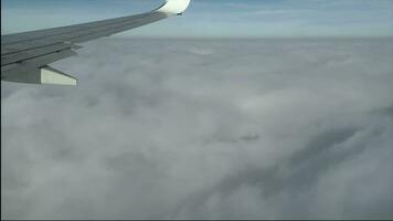 View from the window of the plane. Traveling by air. Wing of an airplane flying above the clouds. Shadow of the plane is visible on the clouds video