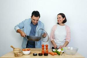 Young couple cooking a plate of food with a white background behind it photo