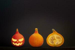 Tres pequeño calabazas con Víspera de Todos los Santos cara mentira en un línea en un gris antecedentes. foto