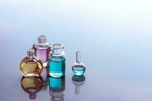 Open aromatic oils in bottles with reflections. Yellow, pink, blue color. Place for text. photo