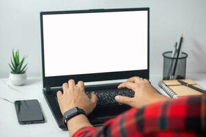 man's hands working on laptop in front of white photo