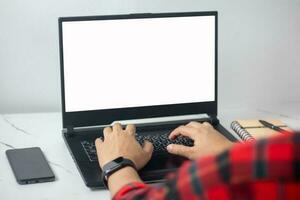 man's hands working on laptop in front of white photo