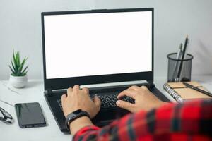 man's hands working on laptop in front of white photo