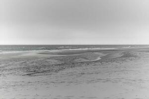 greyscale shot  of  sea and beach at the dutch North Sea photo