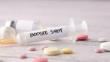 Booster Schuss Prüfung auf Spritze und Tabletten auf Rosa Hintergrund, schließen oben video