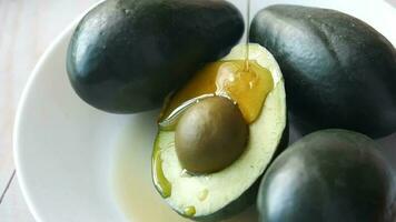 Honey drops on a slice of avocado on wooden table video