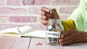 Senior woman saving coins in a jar video