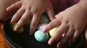 child hand holding a bowl of easter eggs on pink video