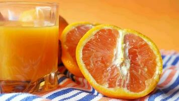 Glass of orange juice and fruit on color background , video