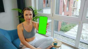 glücklich entspannt Frau im kabellos Kopfhörer Hören zu Musik- und mit Handy, Mobiltelefon Apps oder kommuniziert auf Sozial Netzwerke auf Smartphone video