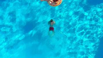 couple ayant amusement dans le piscine, le homme plongées et le femme mensonges sur une Donut video