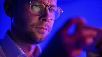 Caucasian Man in His 30s Wearing Glasses Browsing Data on His Smartphone video