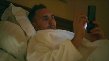 meio envelhecido homem relaxante dentro cama com dele Smartphone video