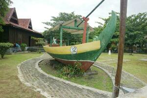 a statue of a green and yellow boat placed in front of a house photo