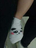 Photo of a baby's foot in a sock with a cute panda face on it