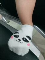 Photo of a baby's foot in a sock with a cute panda face on it