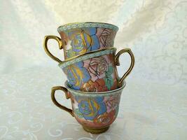 Several vintage cups with floral textures are uniquely arranged on the table photo