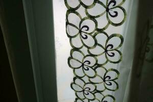 A curtain in front of the window with a transparent color and a flower pattern photo