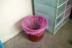 Red trash can covered with pink plastic photo