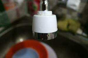 The head of a water faucet that is in the sink photo