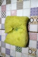 A broken yellow foam used for washing dishes is placed on the tile photo