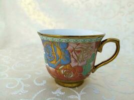 Vintage cups with floral textures are uniquely arranged on the table photo