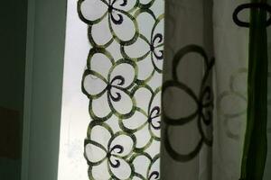 A curtain in front of the window with a transparent color and a flower pattern photo
