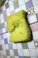un roto amarillo espuma usado para Lavado platos es metido en el loseta foto
