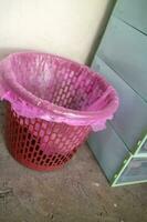 Red trash can covered with pink plastic photo