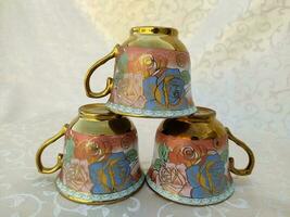 Several vintage cups with floral textures are uniquely arranged on the table photo