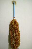 A duster with red yellow feathers, hangs on the wall photo