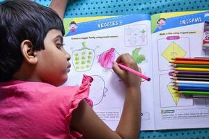 Child engrossed in art, exploring creativity, and filling her book with colorful drawings photo