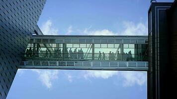 Crowds of people commuting inside modern futuristic sky corridor office building video