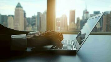 Business person working on laptop computer in modern office with city window view video