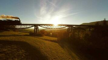 aérien vue de vieux historique vapeur moteur locomotive train traversée une pont route à le coucher du soleil video