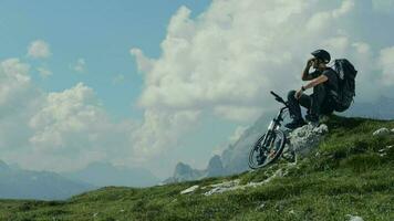 motociclista riposo su il montagna pista e godendo grande panoramico montagna panorama. video