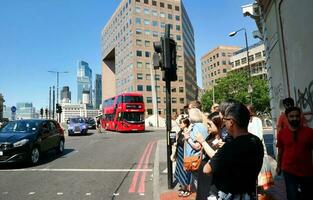 Beautiful Low Angle View of Central London and Road with Traffic and People. The Image Was Captured at Tower Bridge London England Great Britain on Warm Sunny Day of 04-June-2023 photo