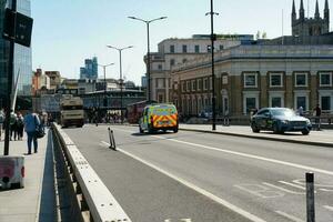 Beautiful Low Angle View of Central London and Road with Traffic and People. The Image Was Captured at Tower Bridge London England Great Britain on Warm Sunny Day of 04-June-2023 photo