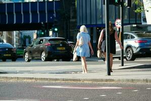 Beautiful Low Angle View of Central London and Road with Traffic and People. The Image Was Captured at Tower Bridge London England Great Britain on Warm Sunny Day of 04-June-2023 photo