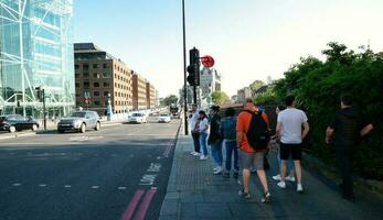 Beautiful Low Angle View of Central London and Road with Traffic and People. The Image Was Captured at Tower Bridge London England Great Britain on Warm Sunny Day of 04-June-2023 photo