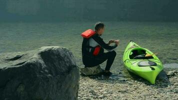 kayaker e il suo kayak su il lago riva preparazione per un altro kayak viaggio video