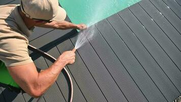 Caucasian Man Washing Composite Deck Around Outdoor Swimming Pool with Garden Hose. Residential Pool Maintenance Theme. video