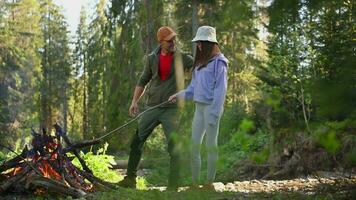 contento caucasico famiglia di i viaggiatori in piedi in giro il fuoco di bivacco nel il foresta. padre avendo un' Chiacchierare con il suo figlia. fine settimana lontano viaggio. video