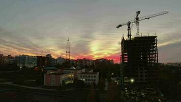 siluetas de ciudad edificios en el antecedentes de un hermosa rojo puesta de sol. noche ciudad. construcción sitio a puesta de sol video
