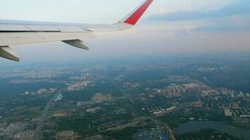 Aerial view of a big modern city. Airplane wing from the porthole of an airliner video