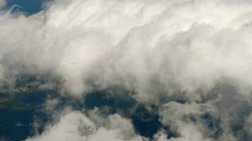 Aerial view from airplane window at high altitude of distant city covered with white puffy cumulus clouds video