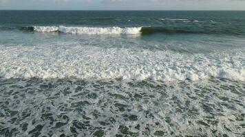 Aerial view of giant ocean waves crashing and foaming in coral beach video