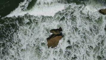 Top down aerial view of giant ocean waves crashing and foaming in coral beach video