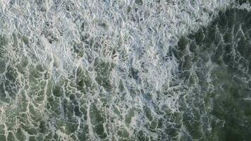 Top down aerial view of giant ocean waves crashing and foaming in coral beach video