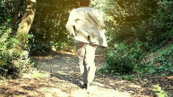 Frightened man running through trees and greenery without looking back, tired man trying to leave forest quickly escape in danger video